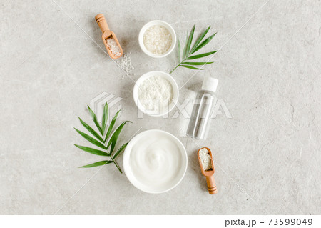 Female skin and body care cosmetic products set: facial cream, cosmetic clay, sea salt, bottle with hyaluronic on gray marble background.  73599049