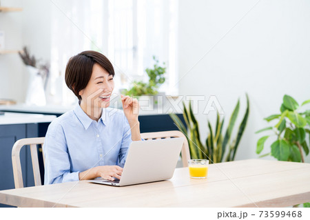 リビングでテレワーク中のミドル女性。 リビングでテレワーク中のミドル女性。 73599468