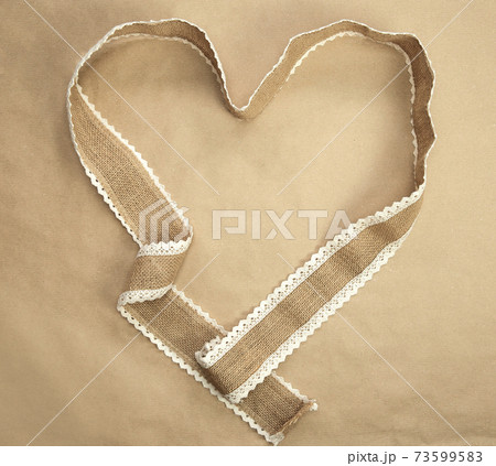 Flat lay design,natural burlap ribbon in heart shape and craft paper background texture, romantic nature Valentine background, Copy space, Valentines Day concept Flat lay design,natural burlap ribbon in heart shape and craft paper background texture, romantic nature Valentine background, Copy space, Valentines Day concept 73599583