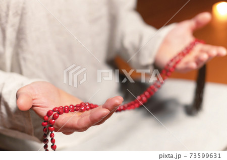 close-up of a male practitioner's hand sitting in lotus position in a dark meditation room with a rosary in his hands close-up of a male practitioner's hand sitting in lotus position in a dark meditation room with a rosary in his hands 73599631