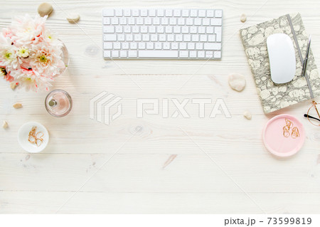 Top view office desk. Workspace with, computer, chrysanthemum, clipboard. Women's fashion accessories isolated on white wooden background. Flat lay Top view office desk. Workspace with, computer, chrysanthemum, clipboard. Women's fashion accessories isolated on white wooden background. Flat lay 73599819