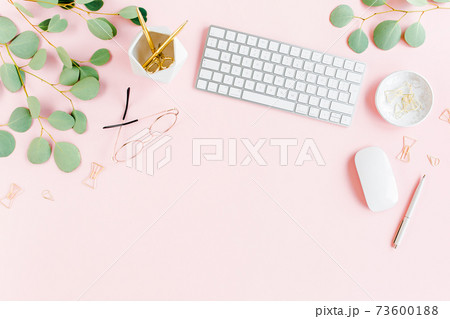 Office table desk with computer, green leaves eucalyptus, clipboard, golden accessories, diary, glasses. Magazines, social media. Top view. Flat lay.  73600188