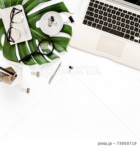 Home office workspace mockup with laptop, tropical leaves Monstera, clipboard, notebook and accessories on white background. Flat lay, top view Home office workspace mockup with laptop, tropical leaves Monstera, clipboard, notebook and accessories on white background. Flat lay, top view 73600719