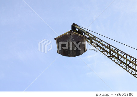 Old yellow mechanical clamshell grab on blue sky background 73601380