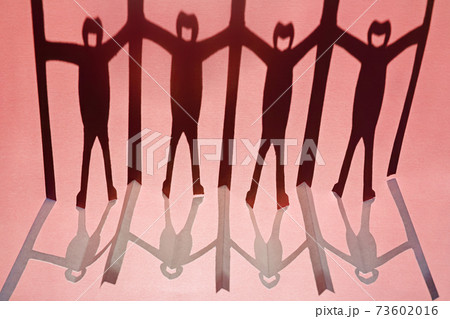 新型コロナ対策で衝立を挟んで繋がる人々の切り紙と影。赤い背景。 73602016