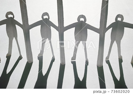 新型コロナ対策で衝立を挟んで繋がる人々の切り紙と影。白い背景。 73602020
