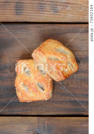 A satisfying meat patty, which combines an airy puff pastry and a delicate pork filling with onions. Baking on a wooden background A satisfying meat patty, which combines an airy puff pastry and a delicate pork filling with onions. Baking on a wooden background 73602164