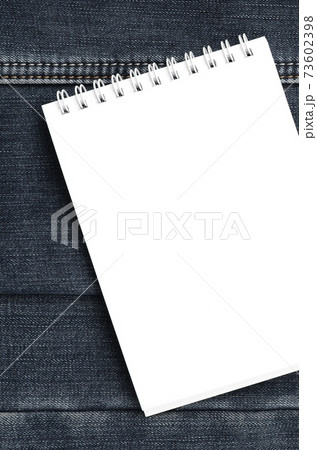 White notebook with clean pages lying on dark blue jeans background. Image with copy space 73602398