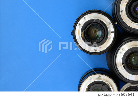 Several photographic lenses lie on a bright blue background. Space for text Several photographic lenses lie on a bright blue background. Space for text 73602641