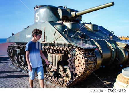 Westkapelle,Netherlands,August 2019. A tank,remnant of the Second World War,serves as a memorial along the road that surmounts the artificial hill that protects the town from the sea.A boy watches him 73604830