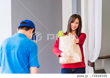 Delivery man making grocery service giving fresh vegetables in paper bag to woman customer 73608566