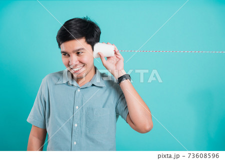 man smile white teeth standing wear shirt, He holding paper can telephone for listening man smile white teeth standing wear shirt, He holding paper can telephone for listening 73608596