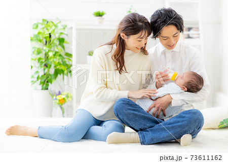 赤ちゃんにミルクをあげる夫婦 73611162