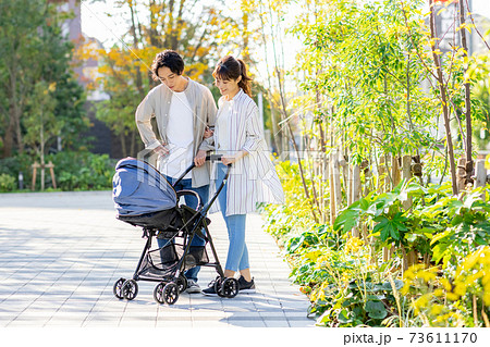 赤ちゃんを抱っこしながら外を歩く夫婦 73611170