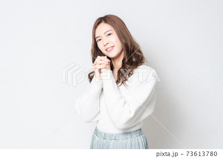 白い壁の前に立って、お願いのジェスチャーをする若い女性 白い壁の前に立って、お願いのジェスチャーをする若い女性 73613780