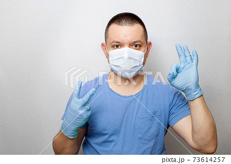 Portrait of young doctor in mask and gloves ok sign isolated on grey background. Portrait of young doctor in mask and gloves ok sign isolated on grey background. 73614257