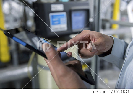 工場でタブレットを操作する作業員男性手元 73614831