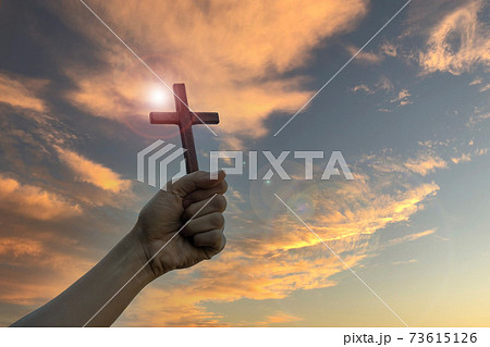Silhouette hand holding wood cross against sunrise background, open palm up worship, pray for blessings from God. Christian Religion, Crucifix and Faith concept 73615126