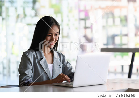 Attractive businesswoman working with laptop computer while sitting in contemporary office. Attractive businesswoman working with laptop computer while sitting in contemporary office. 73616269