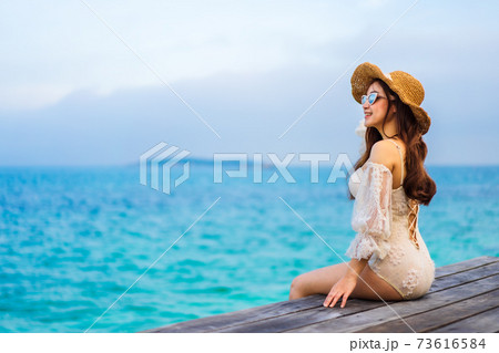 happy woman sitting on a wooden bridge in sea beach at Koh MunNork Island, Rayong, Thailand 73616584