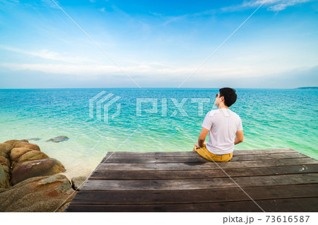 man sitting on a wooden bridge in the sea beach at Koh MunNork Island, Rayong, Thailand man sitting on a wooden bridge in the sea beach at Koh MunNork Island, Rayong, Thailand 73616587