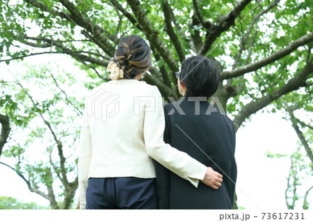 卒業式後に木を見上げる親子 73617231