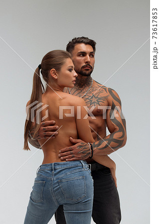 Woman hugging muscular man from behind 73617853