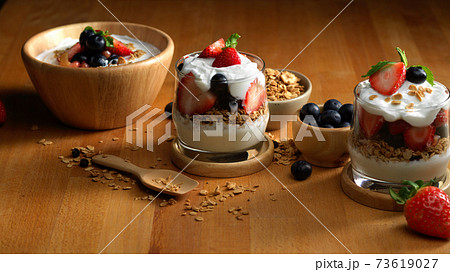 Bowl and glasses of granola with natural Greek yogurt and fresh berries on wooden table Bowl and glasses of granola with natural Greek yogurt and fresh berries on wooden table 73619027