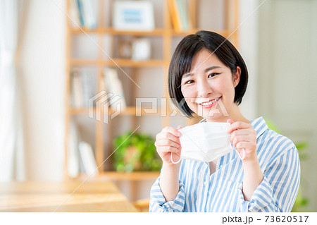 笑顔でマスクを持つ若い女性 笑顔でマスクを持つ若い女性 73620517