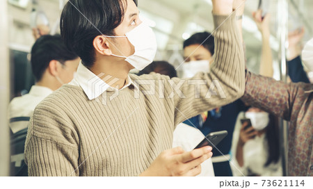 Traveler wearing face mask while using mobile phone on public train 73621114