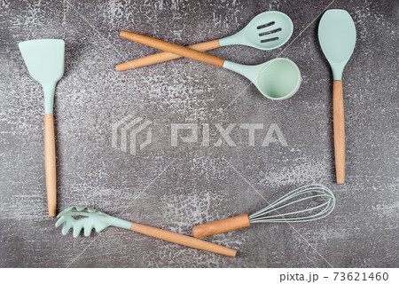 Frame made with kitchen utensils, home kitchen tools, mint rubber accessories on dark background. Restaurant, cooking, culinary, kitchen theme. Silicone spatulas and brushes, free space for text Frame made with kitchen utensils, home kitchen tools, mint rubber accessories on dark background. Restaurant, cooking, culinary, kitchen theme. Silicone spatulas and brushes, free space for text 73621460