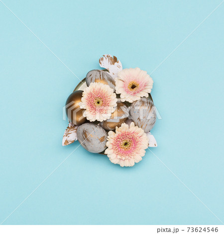 Easter Decoration with gray golden eggs, quail feathers, flowers on blue background. Happy Easter card concept, top view. Easter Decoration with gray golden eggs, quail feathers, flowers on blue background. Happy Easter card concept, top view. 73624546