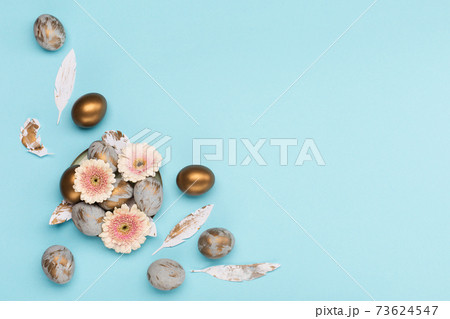 Easter Decoration with gray golden eggs, quail feathers, flowers on blue background. Happy Easter card concept, top view. Easter Decoration with gray golden eggs, quail feathers, flowers on blue background. Happy Easter card concept, top view. 73624547