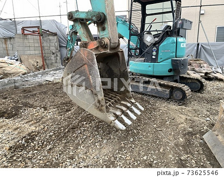 解体現場で仕事をする青緑のショベルカーの写真素材