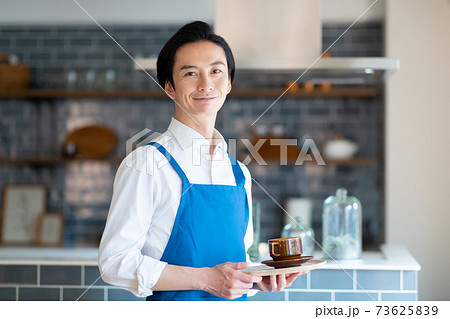 キッチンに立つエプロンをつけた男性の写真素材