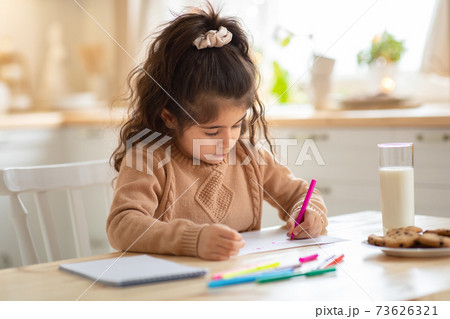 Indoor Portrait Of Small Adorable Girl Drawing Picture At Table In Kitchen 73626321