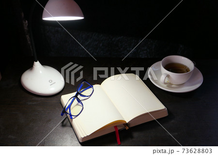 open notepad and table lamp at night  73628803