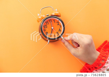 women hand holding alarm clock orange background , 73628805