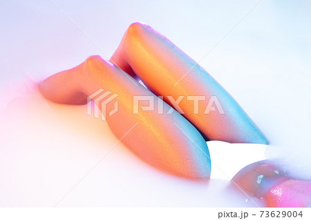 Close up female body in the milk bath with soft glowing in neon light 73629004