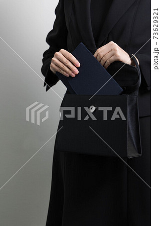 バッグから袱紗を取り出そうとする若い女性の手 【葬儀】 73629321