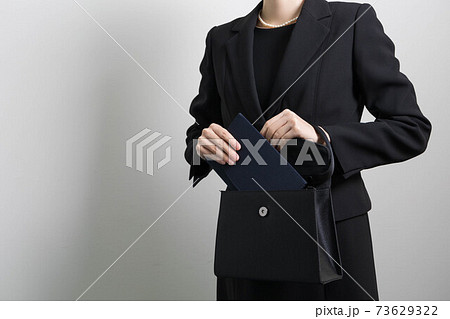 バッグから袱紗を取り出そうとする若い女性の手 【葬儀】 73629322