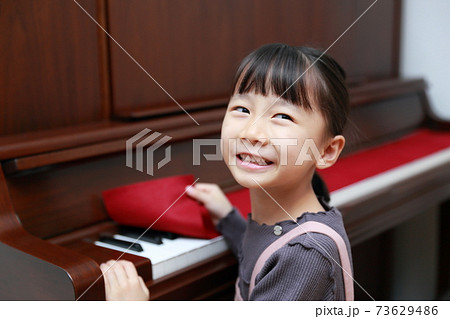 アップライトピアノを弾こうとする5歳の女の子 73629486