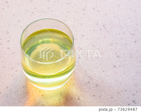 glass of water with yellow solution of vitamin 73629487