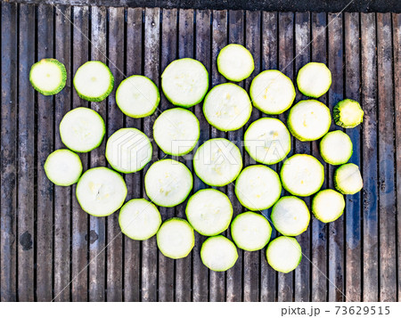 raw fresh slices of zucchini on outdoor grill raw fresh slices of zucchini on outdoor grill 73629515
