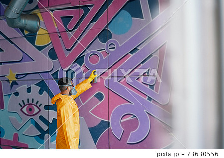 Street artist painting colorful graffiti on wall 73630556