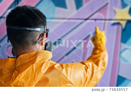 Street artist painting colorful graffiti on wall 73630557