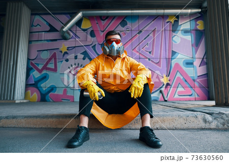 Graffiti painter rest near the wall with his paintings looking to camera 73630560