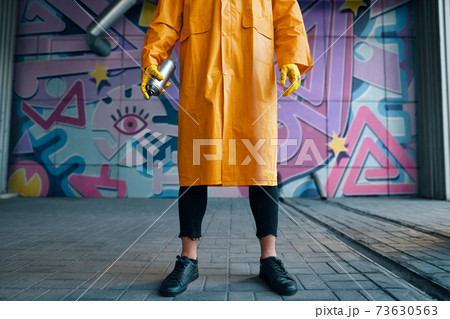 Cropped image of street artist with spray paint can in hand standing near the wall with his paintings 73630563