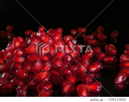 A bunch of pomegranate grains close up. Black background. A bunch of pomegranate grains close up. Black background. 73631900