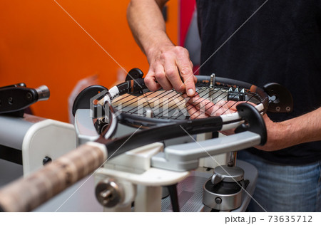The process of stringing a tennis racket in a tennis shop The process of stringing a tennis racket in a tennis shop 73635712